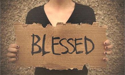 person holding a cardboard sign that says "BLESSED"