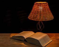 An open book on a table with a lamp light burning