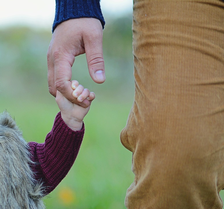 Parent holding hand with child (child grasping tightly to the finger)