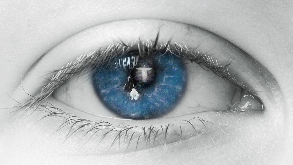 Close-up of a blue eye with reflection of Jesus on the pupil