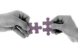 two hands in the process of putting two puzzle pieces together
