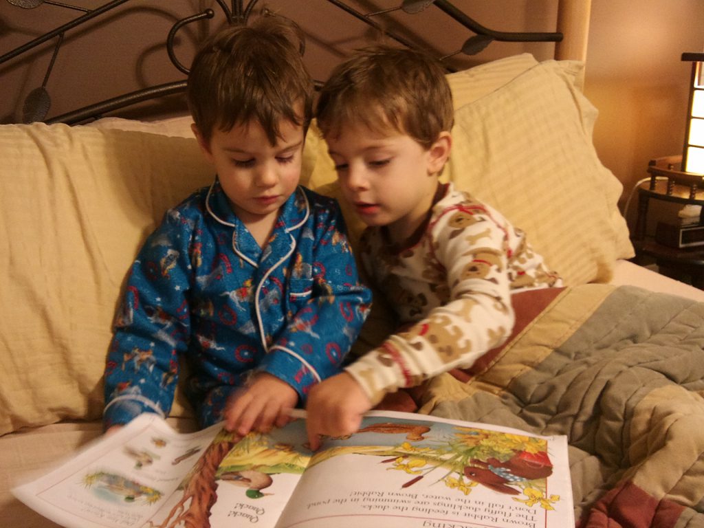 two young boys reading a story book together