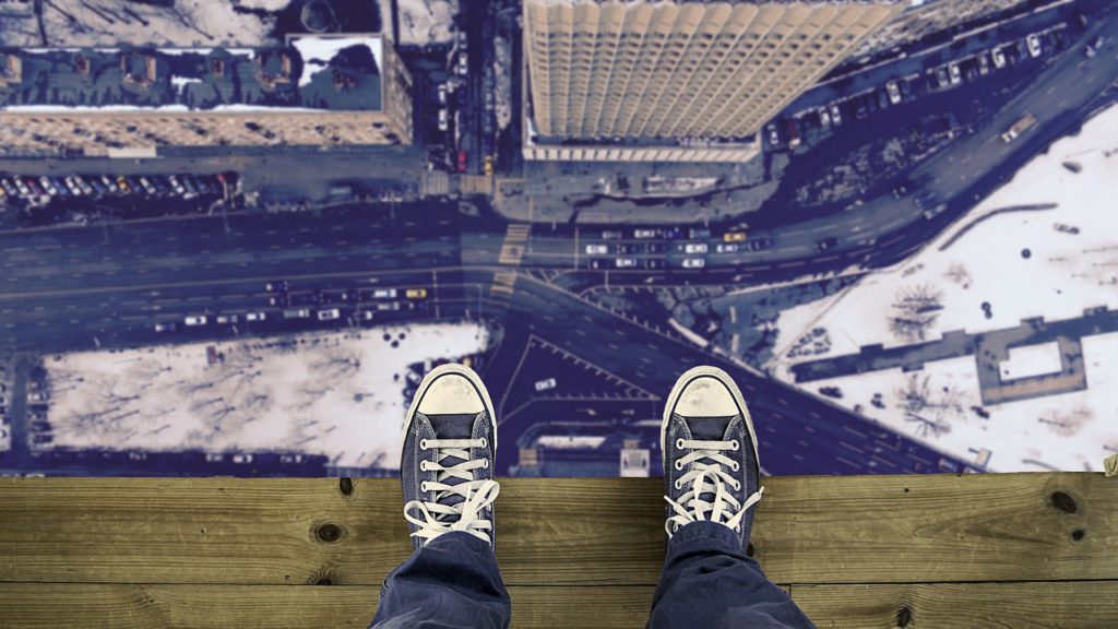 standing on a ledge, looking down at feet and to the street below