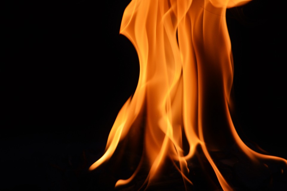 a fire with flame shooting up against a black background