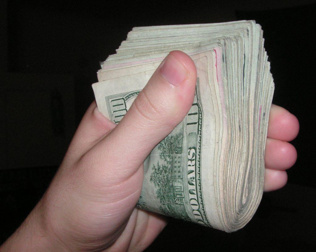 a hand holding a wad of cash