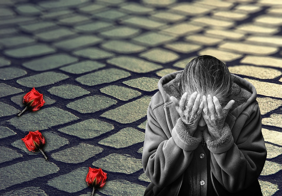woman weeping with head down, grayed out but read rose buds on ground near her