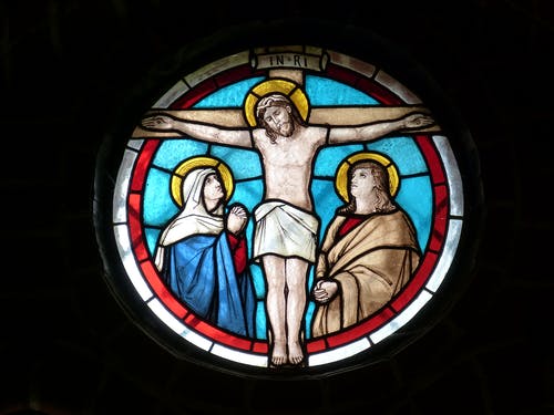 stained glass window with Jesus on the cross and people looking on