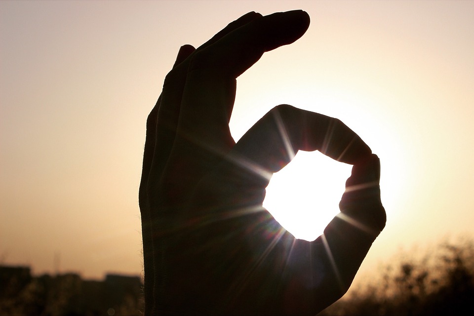 silhouette of a hand doing the ok sign against a sunset