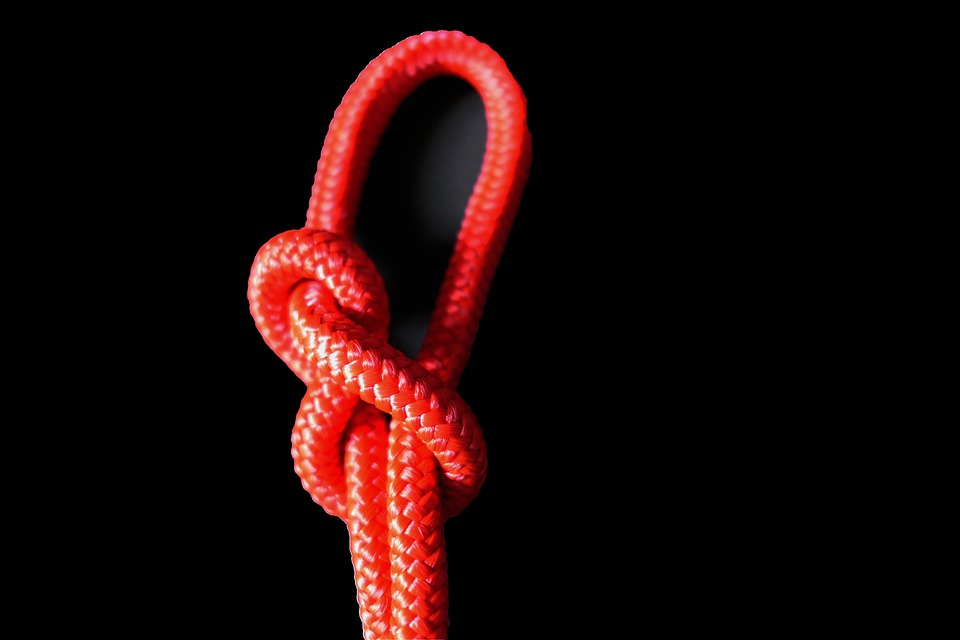 red rope in noose type knot against black background