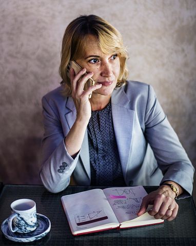 woman talking on the phone with a planner and coffee cup in front of her