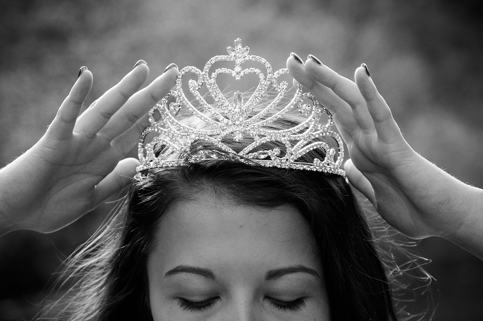 crown being place on woman's head in black and white photo