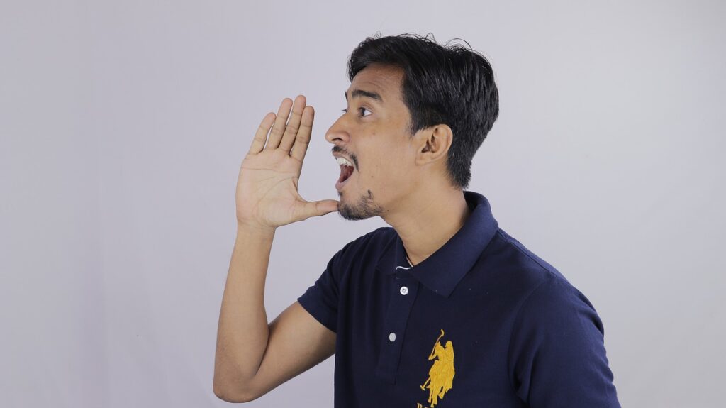 A man with his hand near his mouth, mouth open as if shouting