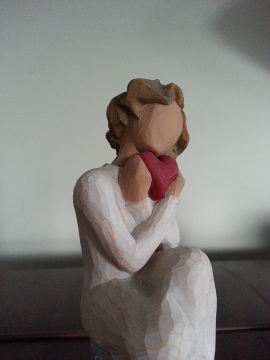 figurine of woman holding heart lovingly