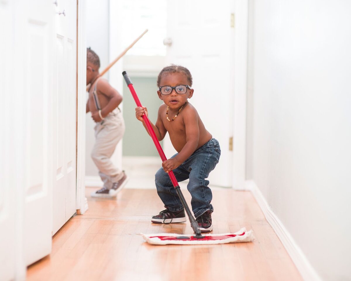 young boy striking a pose with a mop in a hallway