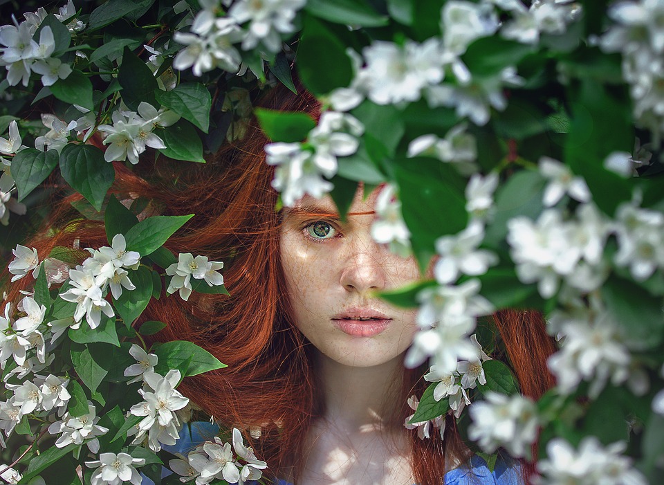 girl peeking out from behind flowers