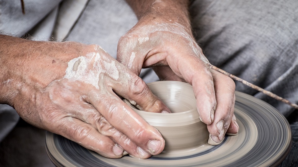 potter's hands forming clay on wheel