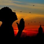 praying while looking up with sunset in the background
