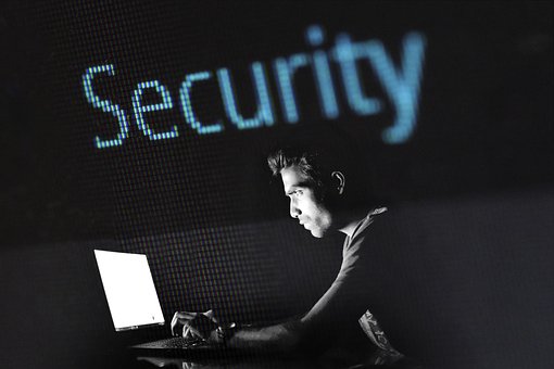 man working in the dark on a computer with the word Security above him