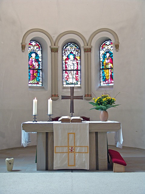 altar with cross, candles, flowers, Bible, and stained glass behind