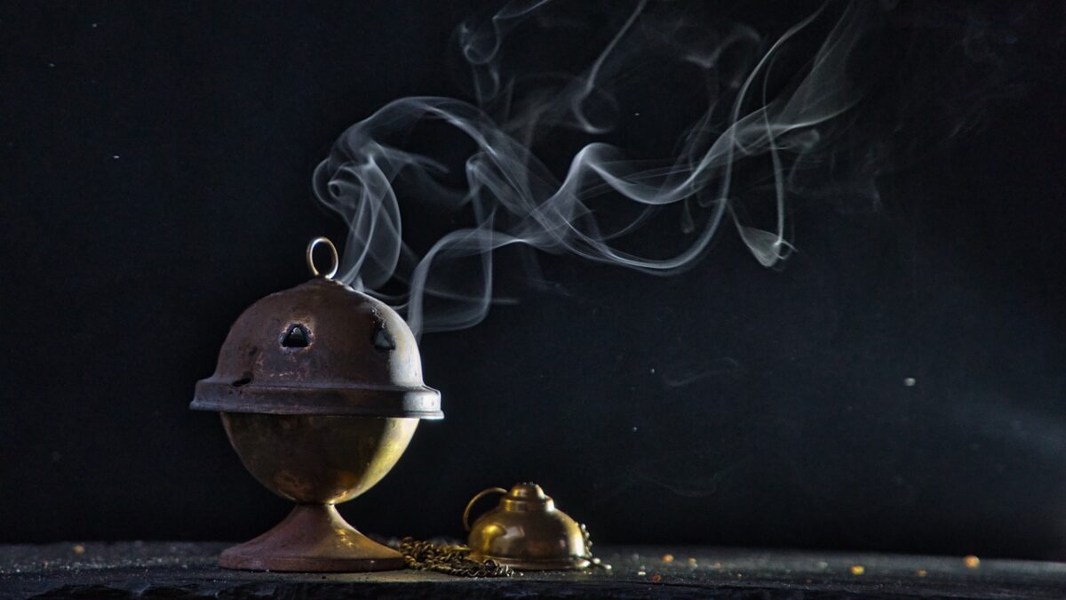 incense burner with gray smoke billowing against black background