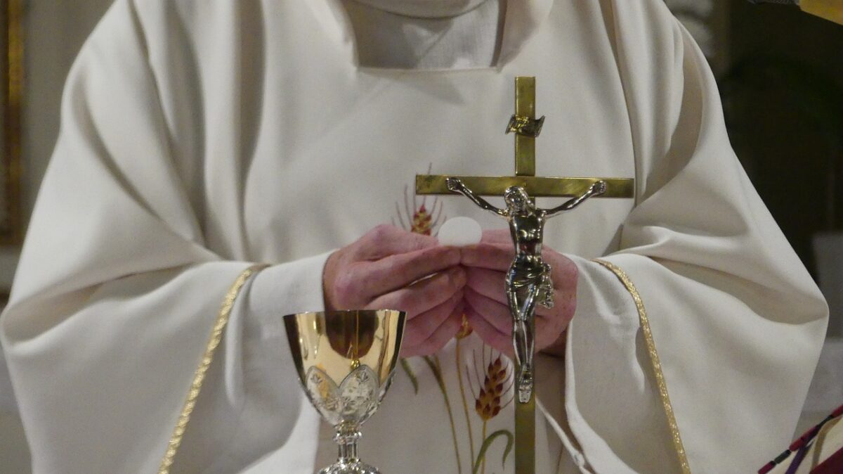 priest in robe with crucifix and communion elements