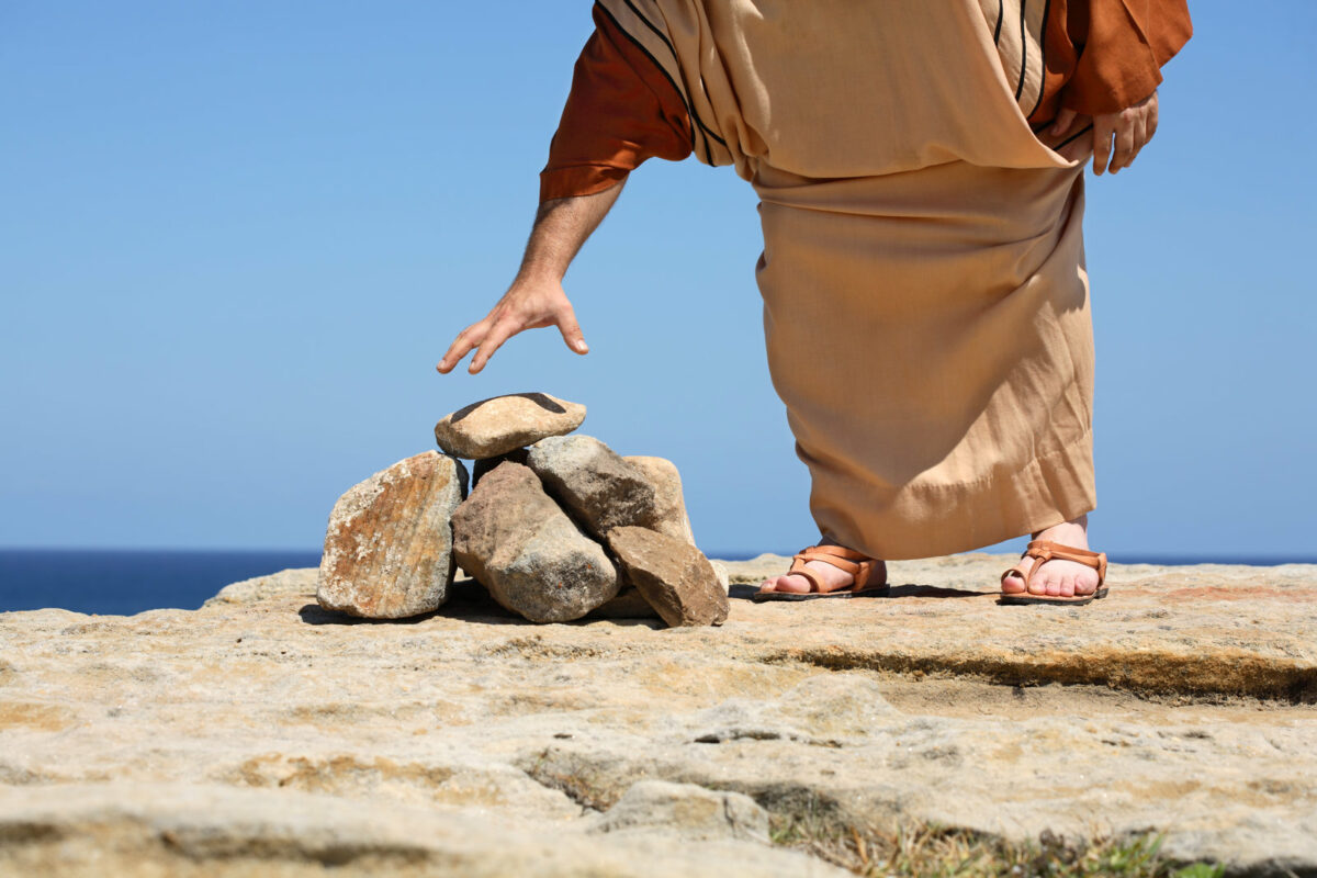 man in robe by pile of stones