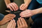 six hands from six pepole all touching the Holy Bible